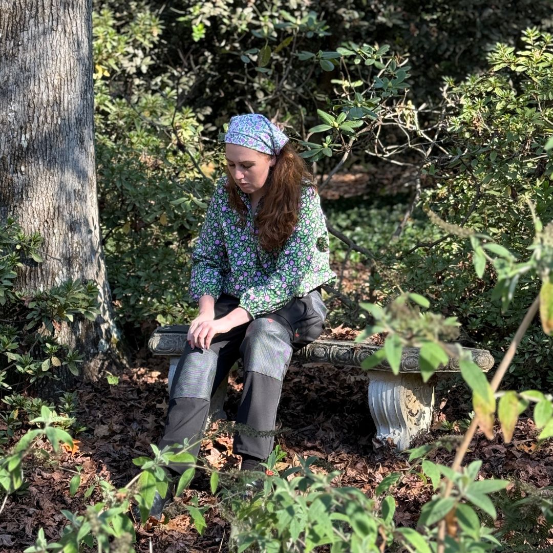 Model wearing the Garden Bravery Brave Bandana in Tearjerker. This versatile 22" square bandana can be worn as a scarf, headband, kerchief, or used as a garden towel, combining elegant style with practical functionality for gardeners. Perfect accessory for fashionable gardening enthusiasts.